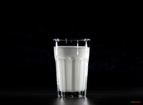 A glass of fresh milk against a black background, emphasizing simplicity and nutrition.